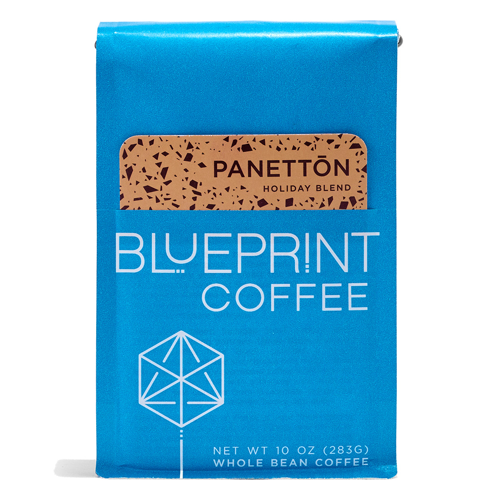 A blue 10-ounce bag of Panettōn Holiday Blend coffee beans featuring the Blueprint Coffee Logo and a removable info card decorated with peach and red flecks.